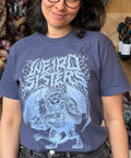 Person wearing a blue t-shirt with a graphic design in front of yarn skeins.