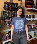 Woman wearing a blue t-shirt with a graphic design in a yarn store.