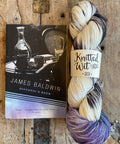 Yarn skein with 'Knitted Wit' label on a book titled 'Giovanni's Room' by James Baldwin.