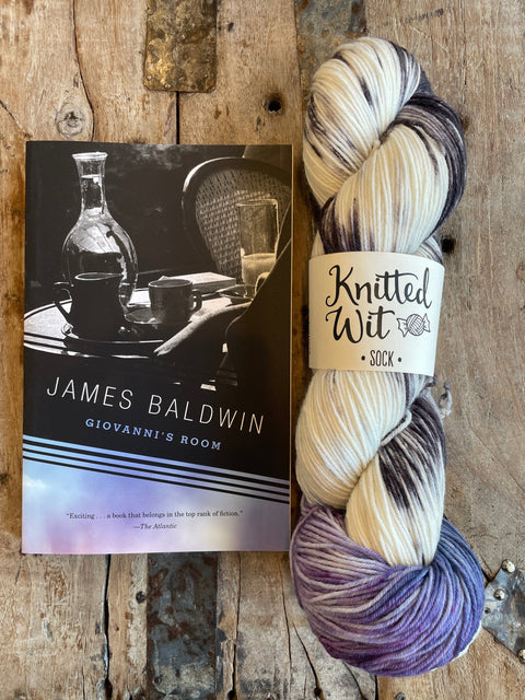 Yarn skein with 'Knitted Wit' label on a book titled 'Giovanni's Room' by James Baldwin.