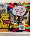 A display of colorful yarn skeins and a sign reading 'CARL SOCK SETS' on a table in a retail or craft shop setting, with a book titled 'Dungeon Crawler Carl' by Matt Dinniman visible on the left.