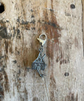 Silver Baba Yaga house shaped charm on a wooden surface