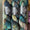 Three skeins of Ex Libris yarn stacked on a rustic wooden surface. The yarn features a variegated color pattern of deep teal, blue, brown, and hints of gold.